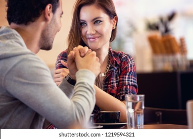 Amorous couple sitting on table and  looking each other in coffee shop