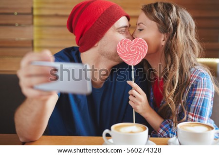 Amorous guy and girl making selfie of their kiss