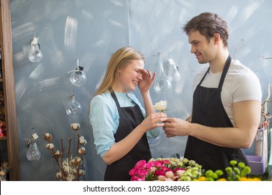 Amorous Shop Assistant Giving Flower To His Embarrased Collegue