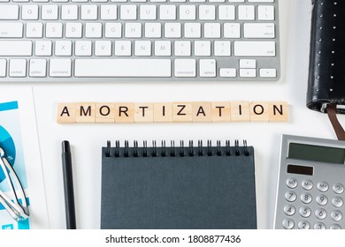 Amortization expense concept with letters. Still life of office workplace with supplies. Flat lay white surface with computer keyboard and calculator. Financial management, accounting and calculation