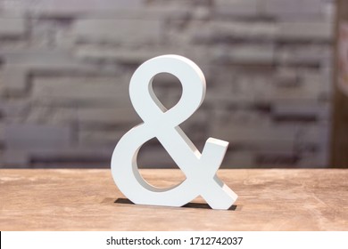 ampersand & sign on wood table with blurred wall background