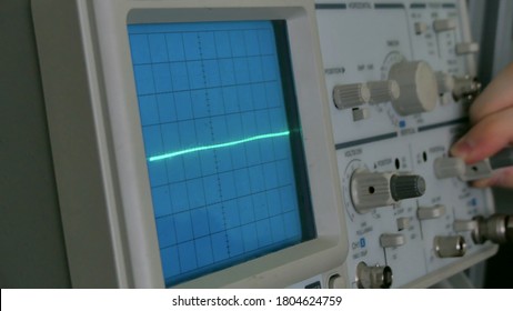 Amplitude Diagram on the oscilloscope. A man presses the buttons on the device. The geometric line changes shape - Shutterstock ID 1804624759