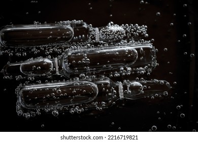 Ampoule Beauty Products.Mesotherapy Serum In Ampoules.Hyaluronic Acid In Ampoules. Ampoules In Bubbles In Water On A Black Background.Cosmetics Medical And Care Concept