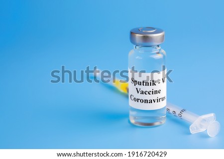 ampoule with virus vaccine with injection syringe on blue background, sputnik-v vaccine for treatment of the virus, coronavirus, SARS-CoV-2, closeup
