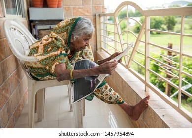 AMRAVATI, MAHARASHTRA, INDIA 19 JULY 2019 : Old Age Traditional Indian Woman Reading A Local News Paper At Balcony Of Her Home In The Morning.