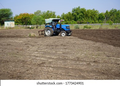 AMRAVATI, MAHARASHTRA, INDIA 7 JUNE 2020 : Unidentified farmer with tractor preparing land for sowing with tractor and cultivator, An Indian farming scene.