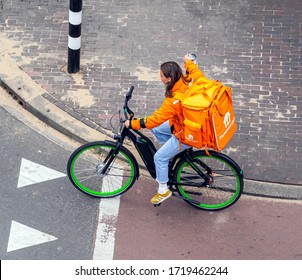 Amsterdam, April 2020 Bicycle Courier Of Thuisbezorgd.nl, The Dutch Branch Of Takeaway.com, On An Electric Bike, On Her Way To A Delivery