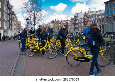 AMSTERDAM - APRIL 4, 2015: Group of unknown tourists on yellow rental bikes in the center of amsterdam