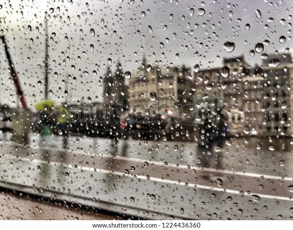 Amsterdam buildings behind\
rainy window