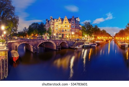 Amsterdam canal, bridge and typical houses, boats and bicycles during evening twilight blue hour, Holland, Netherlands. Used toning.