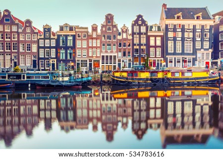 Amsterdam canal Singel with typical dutch houses and houseboats during morning blue hour, Holland, Netherlands. Used toning.