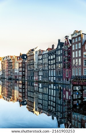 Amsterdam City Scene,  typical dutch houses and their reflection in the canal. Old 17th and 18th century brick houses along a canal in centre of Amsterdam, Netherlands.