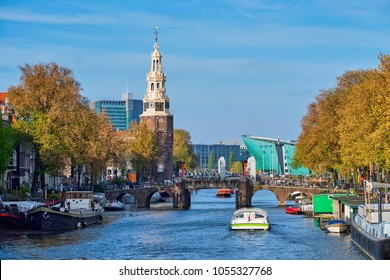 Amsterdam cityscape with canal boats and medieval houses and NEMO Science museum and Montelbaanstoren Tower. Amsterdam, Netherlands