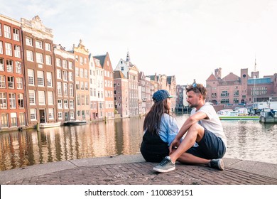 Amsterdam Damrak during sunset, happy couple man and woman on a summer evening at the canals