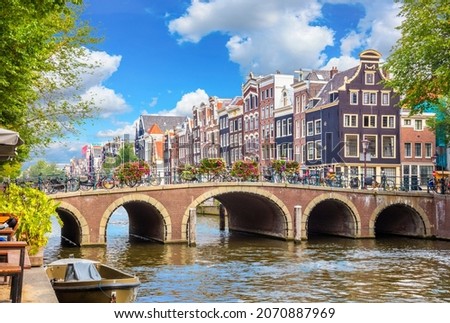 Amsterdam downtown - Amstel river, old houses and a bridge. Nice view of the famous city of Amsterdam. Travel to Europe. Amsterdam, Holland, Netherlands, Europe.