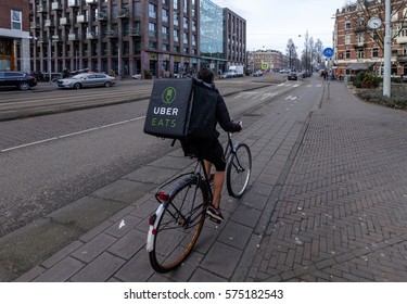 Amsterdam, February 2017: Bicycle Courier From Ubereats With Backpack, On His Way To Deliver A Meal.