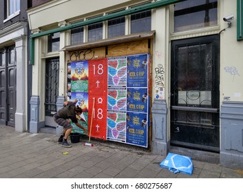 Amsterdam, July 2017. Guy Is Wild Posting Event Posters On The Wall Of A Boarded Up House