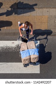 Amsterdam, June 2018. Young Mother With Twins, Pushing Her Double Buggy Across A Zebra Crossing. Seen From Above.