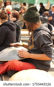 Amsterdam/ The Netherlands :05/14/2010 Street Performer With A Winter Hat, A Hoodie And Dreadlocks Is Sitting Crosslegged And Playing A Pan Like Metal Percussion Instrument Called Hang Or Hang Drum. 