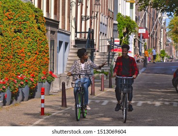 AMSTERDAM, THE NETHERLANDS 30.08.2019.  Two Black African Men Riding Bicycles In Historical Part Of Amsterdam In A Beautiful Summer Day.