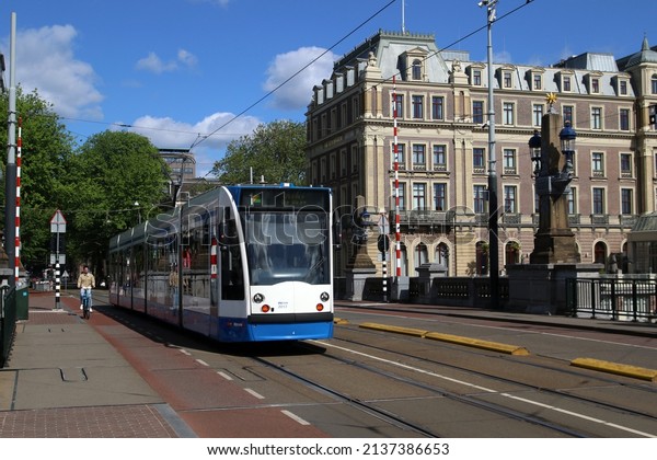 AMSTERDAM, THE\
NETHERLANDS -5 MEI 2020: Tram runs over a bridge with the famous\
Amstel Hotel on the\
right.\
\
