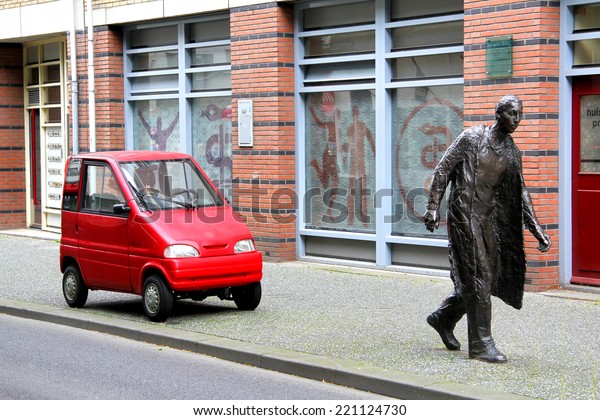 AMSTERDAM, NETHERLANDS -\
AUGUST 10, 2014: Tiny car Canta LX at the city street near the\
statue of a\
pedestrian.