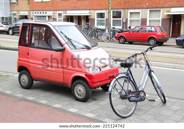 AMSTERDAM, NETHERLANDS - AUGUST 10,\
2014: Tiny car Canta LX at the city street near the\
bicycle.