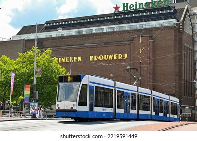 Amsterdam, Netherlands - August 2022: Modern Electric Tram In Amsterdam Passing The Old Heineken Brewery Which Is Now A Museum And Tourist Attraction.