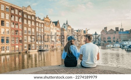 Amsterdam Netherlands during Autumn fall season, a couple of men and a woman visit the city of Amsterdam with orange colors alongside the canal in October. men and women mid age city trip to Amsterdam