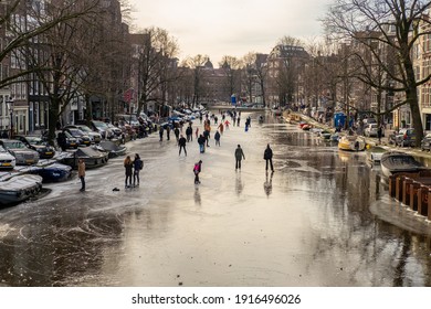 Amsterdam, Netherlands - February 14 2021: People Ice Scating On Frozen Canal In City Center Of Amsterdam