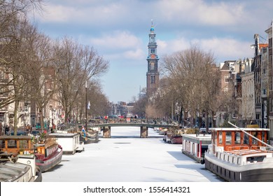 AMSTERDAM, THE NETHERLANDS - February 28, 2018: Winter cityscape in city center with view of canal became frozen and blue sky, Prinsengracht and Westerkerk church and bell tower as backdrop, Holland.