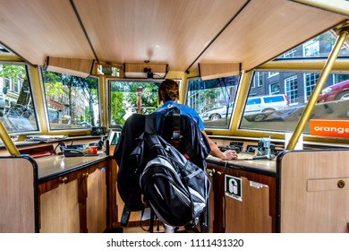 Amsterdam, Netherlands - A Female Tour Boat Operator Pilots A Boat Through The Canals In Amsterdam, Netherlands