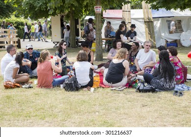 Amsterdam, The Netherlands - July, 5 2015: Friends Meetup Sitting On Grass During Amsterdam Roots Open Air, A Cultural Festival Held In Park Frankendael On 05/07/2015