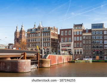 AMSTERDAM, NETHERLANDS - MARCH 19, 2014: Colorful building facades and bridge with walking people. Damrak street in historical center of Amsterdam