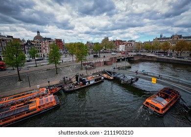 AMSTERDAM, NETHERLANDS - MAY 9, 2017: Aerial View Of Amsterdam Canal With Tourist Boats Near Amsterdam Centraal