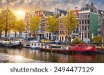 Amsterdam, Netherlands. Panorama of famous dancing houses on river Amstel, water channels with house boats. Popular landmark and travel destination in old european city. Evening sunset landscape