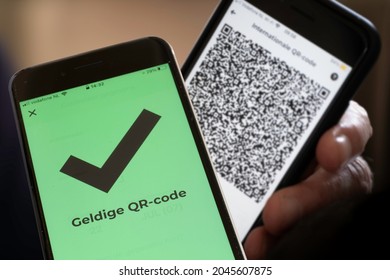 AMSTERDAM, NETHERLANDS - SEPTEMBER 20 2021: Dutch text "Valid QR code" on the green screen of a smartphone meaning the owner of the other phone has been vaccinated or tested negative