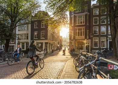  Amsterdam, Netherlands - September 22, 2021: Early morning in Amsterdam. People ride bicycles, the ancient European city of Amsterdam. Sunlight and silhouettes, beautiful downtown 
