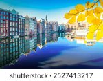 Amsterdam scenety with canal Damrak with typical dutch houses and boats at morning blue hour, Holland, Netherlands at fall day