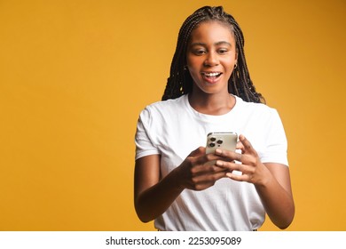 Amused attractive woman using smartphone, looks at the screen surprised and smiles, a female got an unexpected pleasant deal or notification, looks at the phone amazed with open mouth, isolated - Shutterstock ID 2253095089