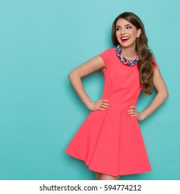 Amused beautiful young woman in pink mini dress posing with hand on hip and looking away. Three quarter length studio shot on turquoise background. - Shutterstock ID 594774212