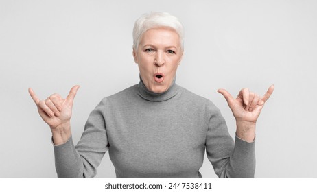 Amused senior european woman makes jumbo gesture on grey background, expressing approval or agreement for s3niorlife
