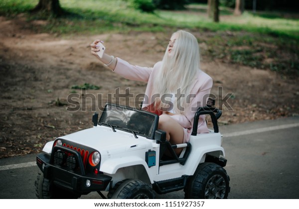 Amusement Park.\
Games. Holiday. Vacation. Game machine. baby machine. Beautiful\
Smiling woman driving car. Outdoor portrait of pretty student girl\
taking a selfie.\
selfie.