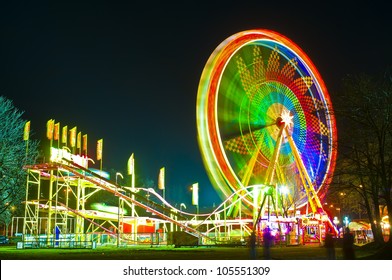 Amusement Park At Night - Ferris Wheel And Rollercoaster In Motion