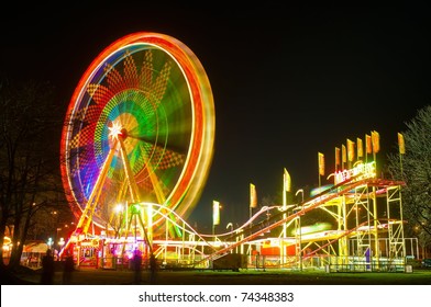 Amusement Park At Night - Ferris Wheel And Rollercoaster In Motion