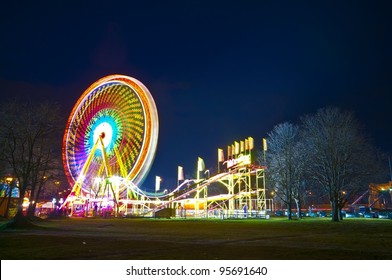 Amusement Park At Night - Ferris Wheel And Rollercoaster In Motion