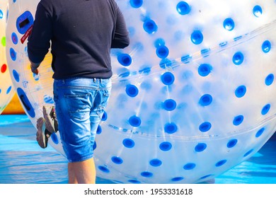 An Amusement Park Worker With A Large Plastic Inflatable Ball