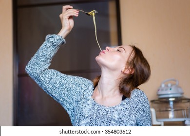 Amusing Attractive Young Woman In Grey Knitted Sweater  Eating Pasta In Kitchen At Home