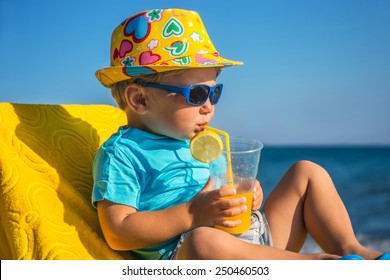 Amusing kid drinks juice from tubule against sea in sunny day - Powered by Shutterstock