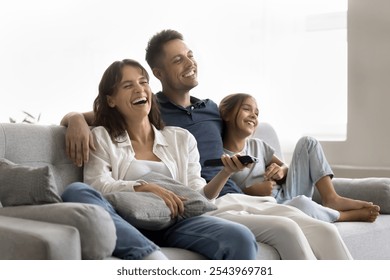 Amusing program. Relaxed friendly family young husband wife tween age girl daughter sit close on comfy couch hug watch television having fun laughing on hilarious telecast enjoy comedy tv show cartoon - Powered by Shutterstock